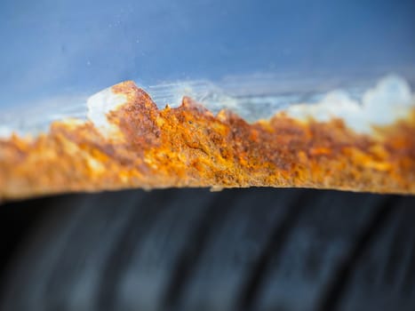 Extreme closeup of orange and brown rust on vehicle above tire