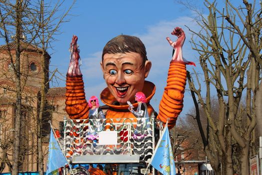 Poggio Renatico, Italy - 01 march 2015: The parade of carnival floats with dancing people on streets. A fake astronaut exults arrival on earth