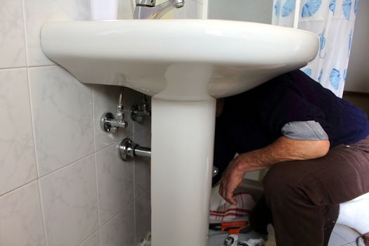 plumber fixing a drain of the sink