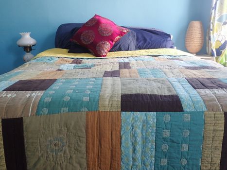 Blue bedroom with throw pillow and summer quilt.
