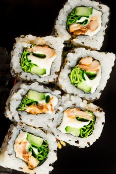 six Japanese rolls on a black dish