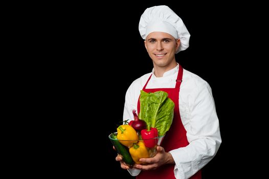 Male chef holding glass bowl full of vegetables