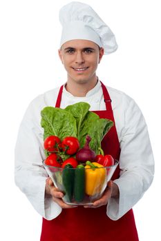 Skilled male chef holding vegetables bowl