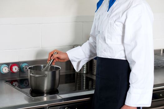 Cropped image of a chef cooking in the hotel kitchen