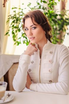 Beautiful business woman sitting at table in light blouse.