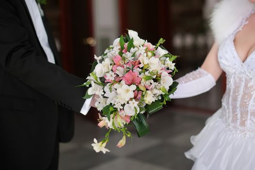 Bride and groom holding bridal bouquet close up.