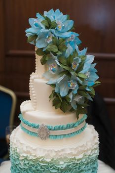 beautiful turquoise three-tiered wedding cake with flowers on top.