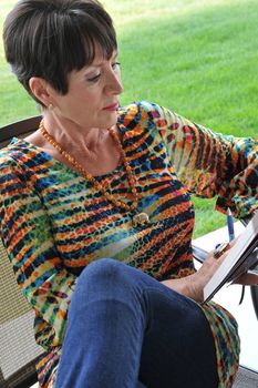 Mature female beauty reading a book outside.