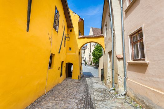 Sighisoara, Romania - June 23, 2013: Old stone paved street with tourists from Sighisoara fortress, Transylvania, Romania