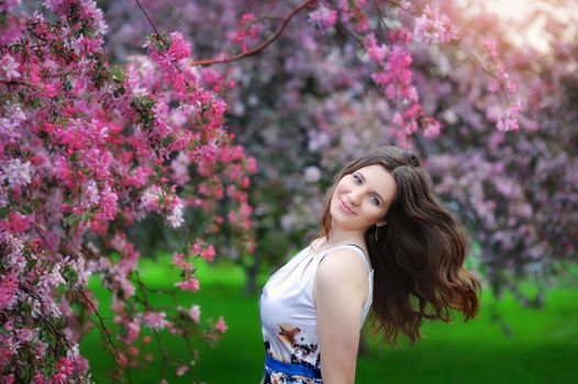 Beautiful young girl in spring flowers garden lifestyle portrait.