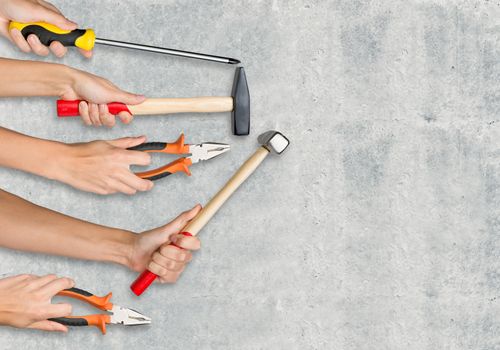 Peoples hands holding different tools on grey background