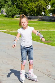 Learning girl on roller skates in summer