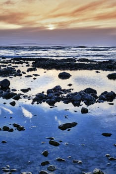 reflections at rocky beach near ballybunion on the wild atlantic way ireland with a beautiful yellow sunset