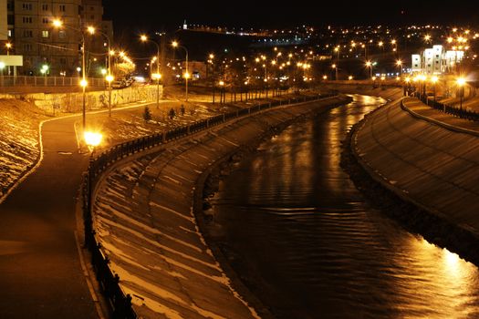 River embankment, illuminated by lights at night