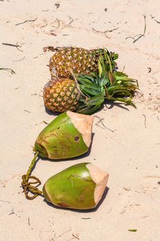 exotic fruit. coconuts and pineapples on the sand