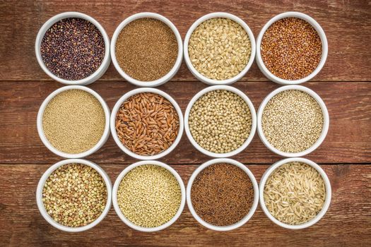 healthy, gluten free grains collection (quinoa, brown rice, millet, amaranth, teff, buckwheat, sorghum) , top view of small round bowls against rustic wood