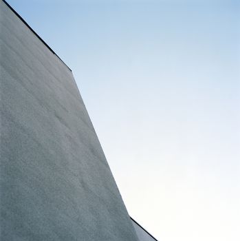 Looking up at the modern architecture of a monochromatic exterior wall 
