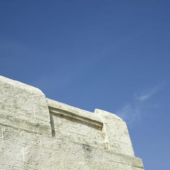Brickwal made of rough sandstone against blue sky