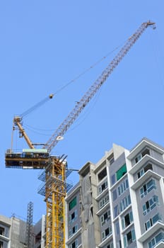 Big crane and incomplete skyscraper with blue sky as background.