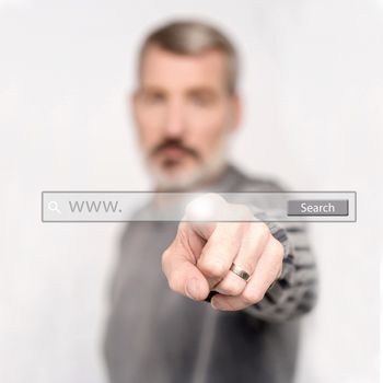 Senior man touching web search bar on virtual screen.