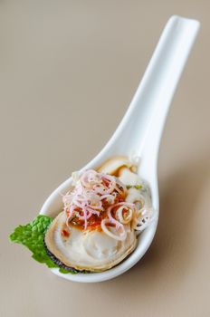 giant mussel with spicy chili sauce on spoon
