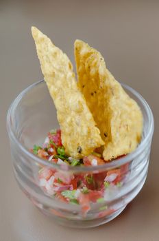 Tortilla chips with salsa dip in cocktail glass