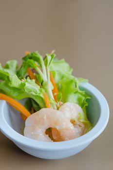 Oak leaf lettuce salad with shrimps in blue bowl