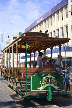 IQUIQUE, CHILE - JANUARY 22, 2015: Unidentified people getting off an old open tram waggon with wooden seats on Plaza Prat main square along Baquedano avenue on January 22, 2015 in Iquique, Chile