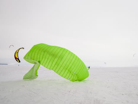 Kite surfer being pulled by his kite across the snow