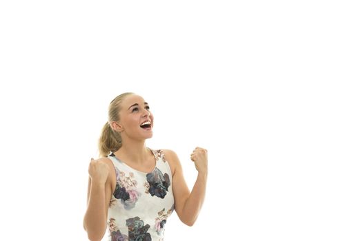 Elated jubilant young blond woman cheering and punching the air with her fists as she looks up with an excited grateful expression, isolated on white with copyspace