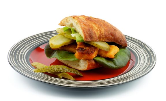 Homemade Fish Burger with White Fish Sticks, Lettuce, Gherkins and Whole Wheat Bread on Red Stripped Plate isolated on white background