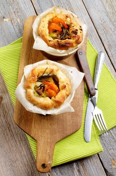 Delicious Puff Pastry Snacks with Shrimps, Leek and Cheese Oven-Baked in Ramekin on Wooden Cutting Board with Fork and Knife