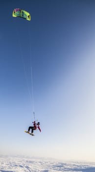 Kite surfer being pulled by his kite across the snow