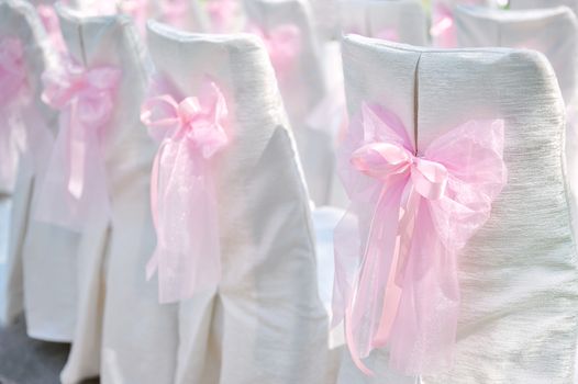 Decoration on wedding chairs pink bow in summer park 