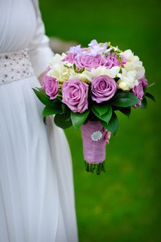 Bridal bouquet of purple roses in bride's hands.