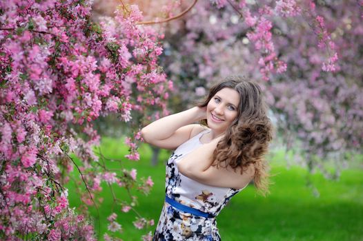 Beautiful woman walking in blossoming spring garden