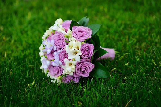 Beautiful wedding bouquet t lie on the grass.