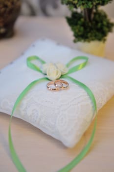 Wedding rings on a cushion with green bow.