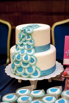 Two-tiered wedding cake with blue ribbons on table.