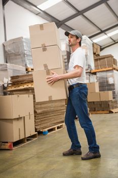 Side view of worker carrying boxes in warehouse