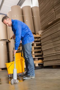 Portrait of focused man moping warehouse floor