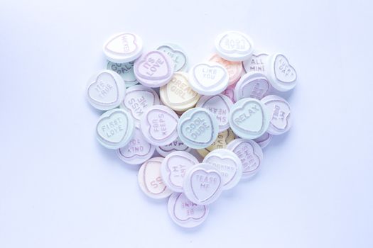 Sweets with text in a heart shape against a white background. This type of confectionary is produced by Swizzles Matlow in the UK.