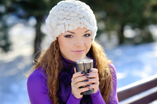 beautiful girl sitting on a bench with a cup of coffee. Winter