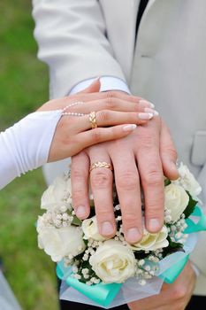 Hands with wedding rings and wedding bouquet.