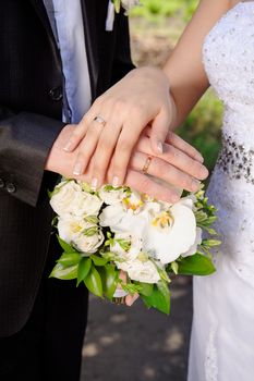 hand the bride and groom with rings on wedding bouquet.
