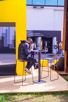 MILAN, ITALY - APRIL 16: Young man looking his smartphone while sitting at outdoor restaurant coffee open air cafe at Tortona space location during the Milan Design week on April 16, 2015