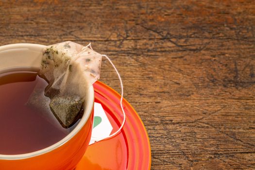 stoneware cup of herbal green tea over rustic wood with a copy space