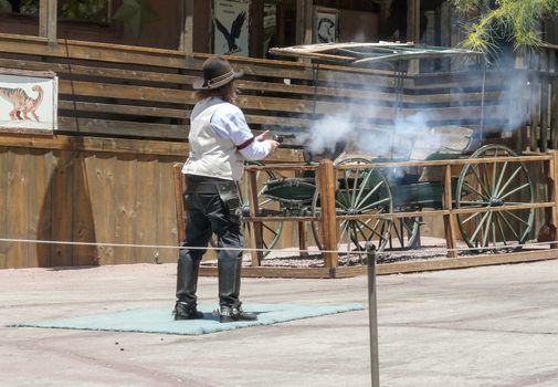 Calico, CA, USA - May 18, 2008: Cowboy (maybe sheriff) shooting with gun at old carriage in Calico Ghost Town, abandoned and obsolete silver mining town in the Mojave desert.