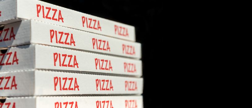 Large stack of pizza boxes. Isolated over black.