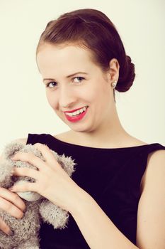 attractive smiling brunette holding teddy bear in a black dress , retro color
